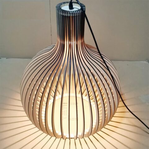 Lustre DIY en bois massif de bambou, assemblé et allumé, sur fond beige.