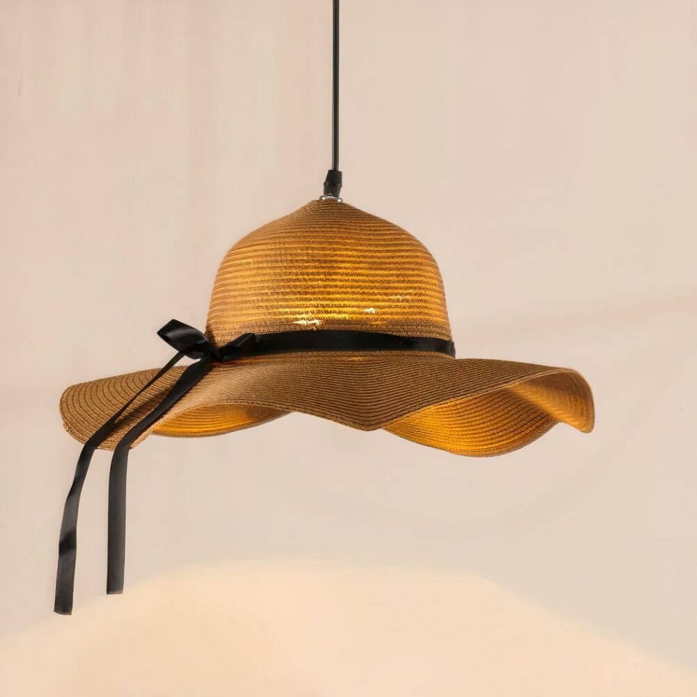 Lustre original chapeau de paille allumé et suspendu sur fond beige clair.