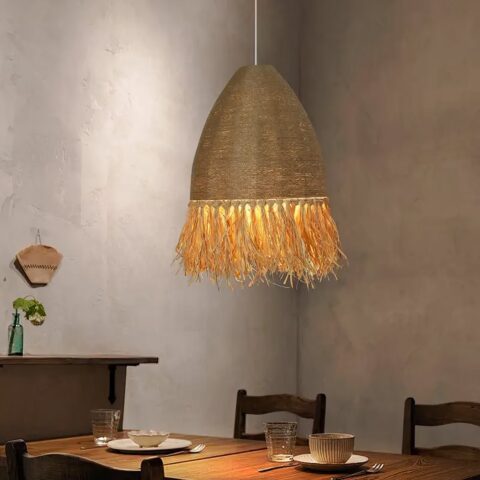Lustre en paille et corde fait à la main suspendu et allumé au-dessus d'une table de salle à manger dressée pour le repas.