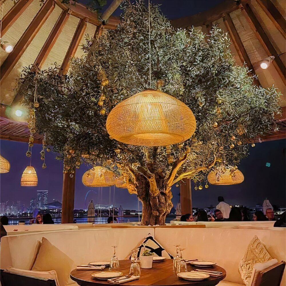Suspensions en bambou tissé au-dessus d'un olivier dans une terrasse de restaurant