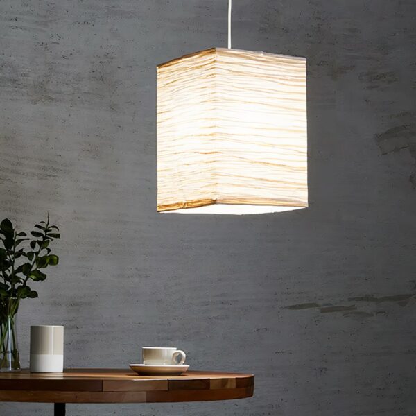 Suspension papier japonais style lanterne traditionnelle suspendue dans un salon et allumée, sur fond gris.