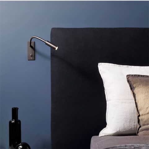 Applique murale liseuse avec interrupteur accrochée à un mur bleu d'une chambre et à côté d'un lit.
