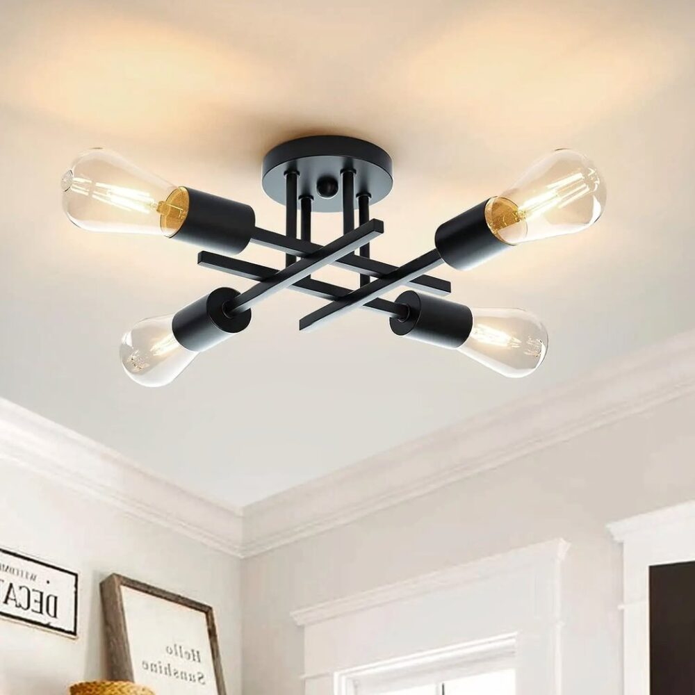 Lustre plafonnier en métal noir avec tiges noires qui se croisent en carré avec ampoules sur une extrémité de chaque tige Des cadres blancs en bas à gauche et encadrements de portes à droite