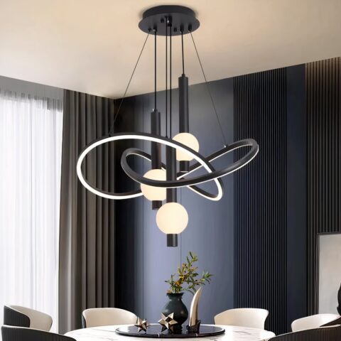 Lustre noir avec support noir fixé au plafond d'où descendent des câbles tenant des structures arrondies entrelacées lumineuses et noires à l'extérieur. Au centre de ces structures, sont pendus des tubes noirs avec une boule lumineuse allumée. Fixé au-dessus d'une table blanche ronde style marbre, avec plateau noir rond, un vase dessus et des objets de décoration. 6 fauteuils autour de la table,à gauche une baie vitrée avec un rideau gris et le mur en face est bleu canard avec des rainures verticales.