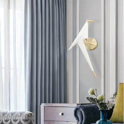 on voit dans un salon aux tons gris une applique murale en origami et en forme d'oiseau blanche et dorée