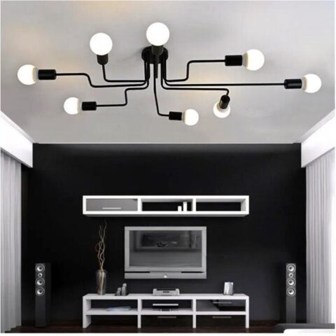 on voit dans un salon aux tons gris et noir un lustre plafonnier à plusieurs têtes dans le style industriel