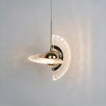 on voit sur un fond gris clair une suspension en forme de planète rotative dorée et transparente