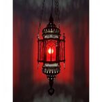 on voit sur un fond rouge une suspension en verre rouge dans le style marocain allumée