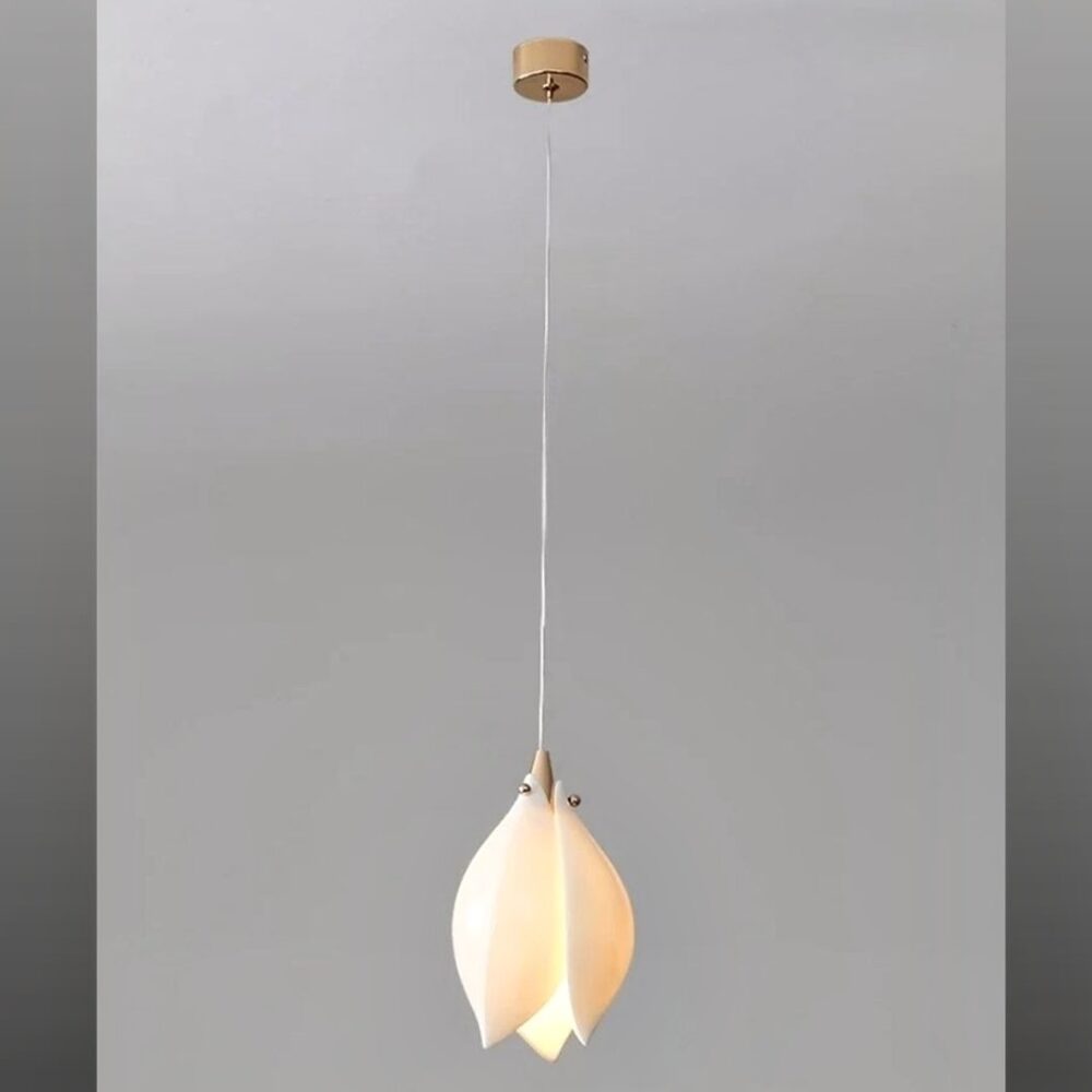 Suspension fleur blanche en céramique forme magnolia accrochée au plafond et allumée, sur fond gris.