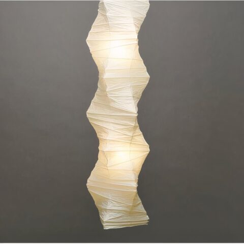 Grande suspension blanche en papier plissé japonais allumée et sur fond gris.