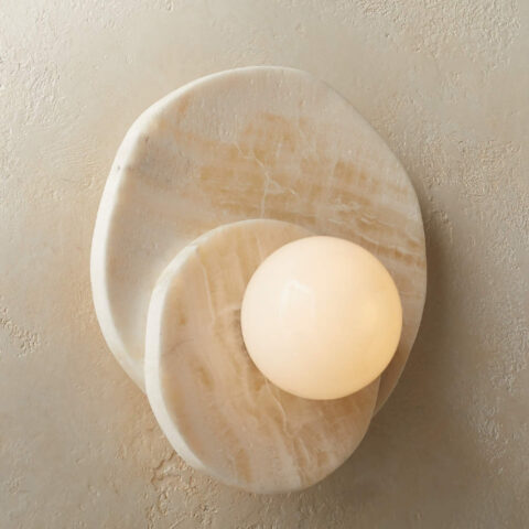 Applique murale circulaire en pierre naturelle de couleur beige avec deux ronds en pierre l'un sur l'autre. Au centre, une boule lumineuse. L'applique est fixée sur un mur beige.