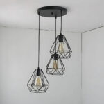 Lustre 3 suspensions géométriques en métal noir de style industriel. Fixé sur un plafond gris.