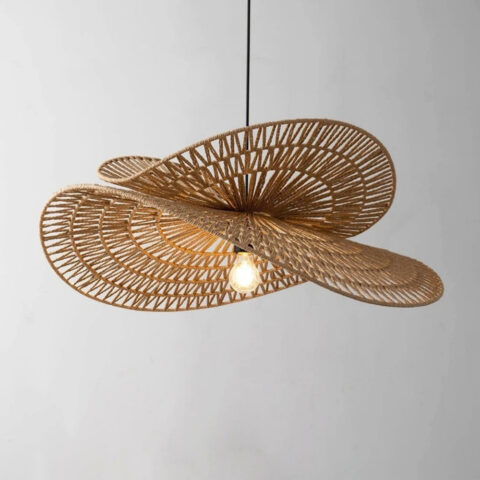 Lustre en rotin style chapeau à deux niveaux avec une ampoule allumée au centre. Le mur à l'arrière est gris.