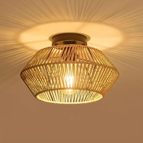 Lustre plafonnier en rotin beige ou noir de forme ronde allumé et fixé sur un plafond beige.