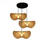 Suspension 3 lampes en rotin de style chapeau avec une ampoule allumée sur chacune des lampes. Suspendues sur un socle rond noir. Sur fond blanc.