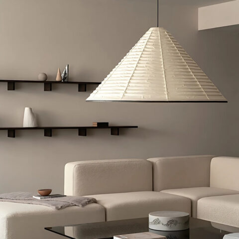 Suspension en papier japonais en forme de cône beige dans un salon avec un canapé d'angle beige. A l'arrière des étagères marron sont fixées sur le mur.