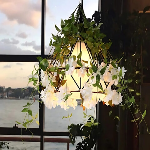 Suspension jungle de forme triangulaire avec feuillage allumée devant une fenêtre.