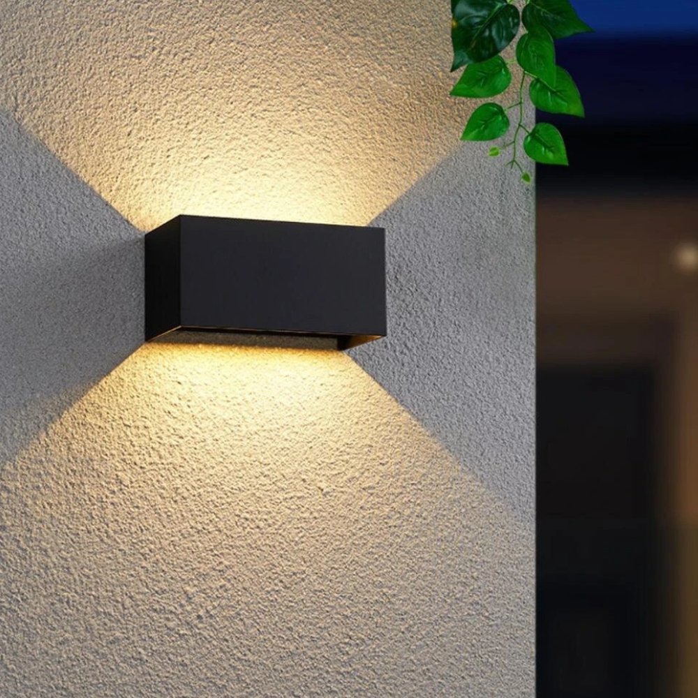 Applique murale LED minimaliste noire, conçue pour une installation extérieure, offrant un éclairage chaleureux avec un double faisceau lumineux.