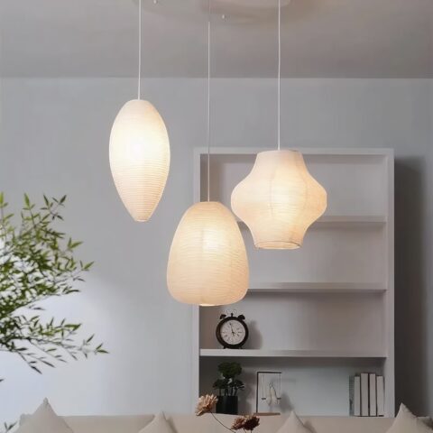 Lustre suspendu Japandi à trois formes en papier blanc, éclairage doux, dans un salon minimaliste.