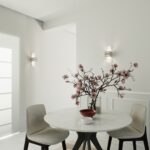 Deux appliques à ailes en verre encadrant une entrée avec table et fleurs
