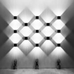 Grille d'appliques cubiques en quinconce éclairant un mur au-dessus de plantes