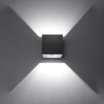 Applique cube noire projetant un faisceau lumineux en croix sur le mur