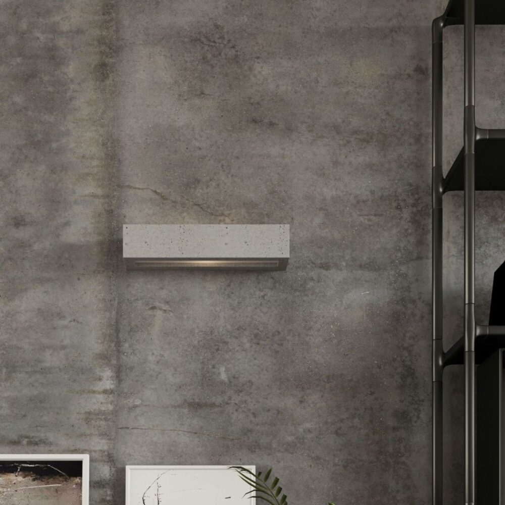 Gros plan sur l'applique en béton fixée à un mur gris texturé avec lumière dirigée vers le bas