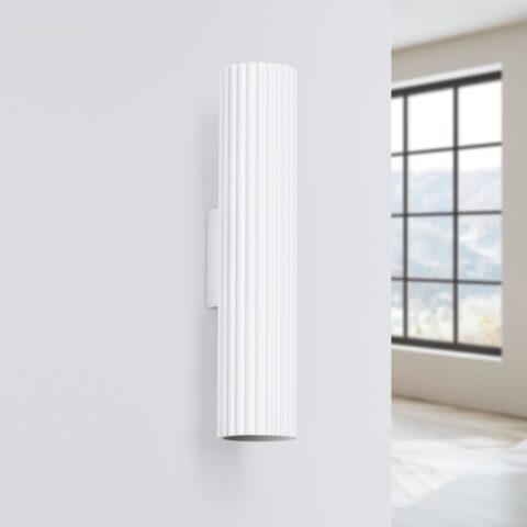 Applique murale blanche en forme de cylindre nervuré en métal sur un mur blanc