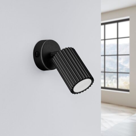 Applique murale noire style spot orientable en métal sur un mur blanc