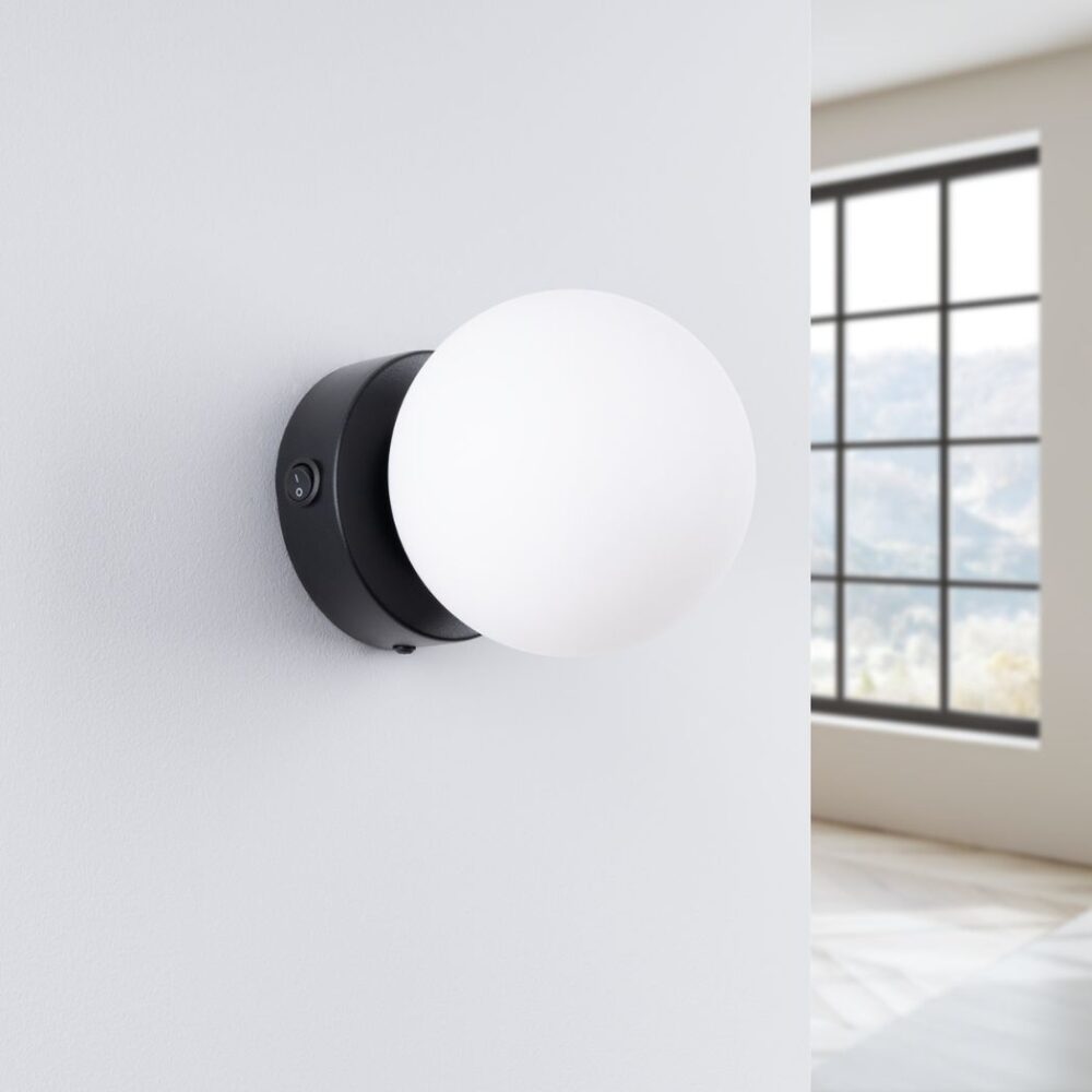 Applique murale ronde et minimaliste en forme de globe en métal noir et verre sur un mur blanc