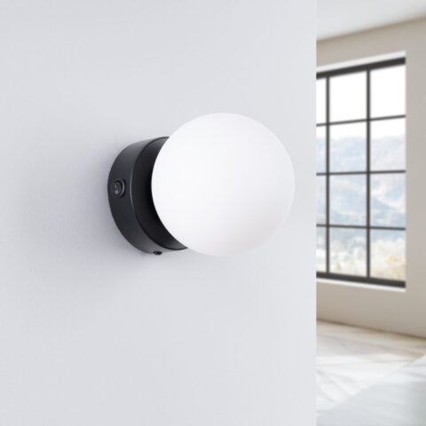 Applique murale ronde et minimaliste en forme de globe en métal noir et verre sur un mur blanc