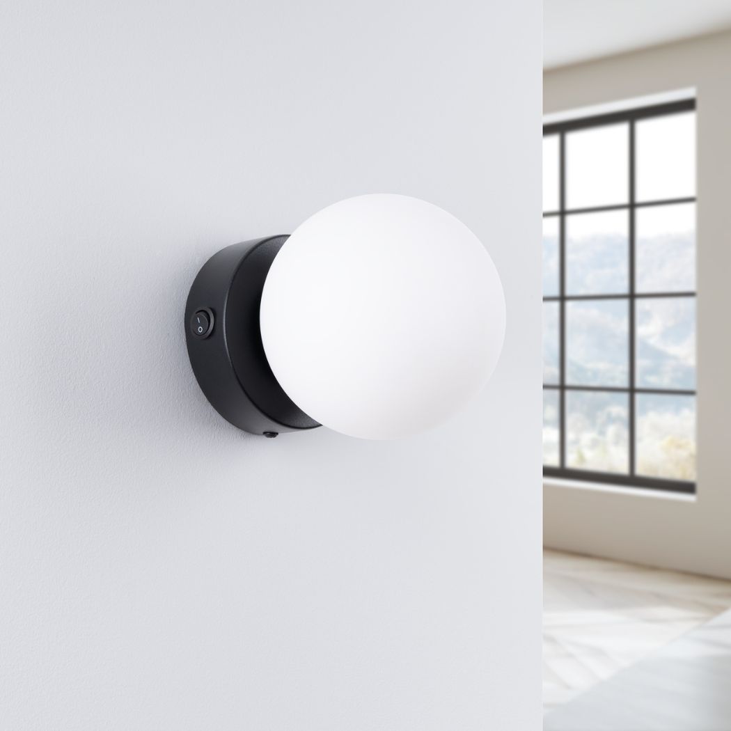 Applique murale ronde et minimaliste en forme de globe en métal noir et verre sur un mur blanc