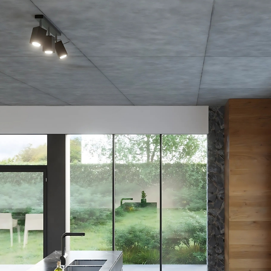 Plafonnier noir à trois spots orientables sur un plafond en béton au-dessus d'un îlot de cuisine