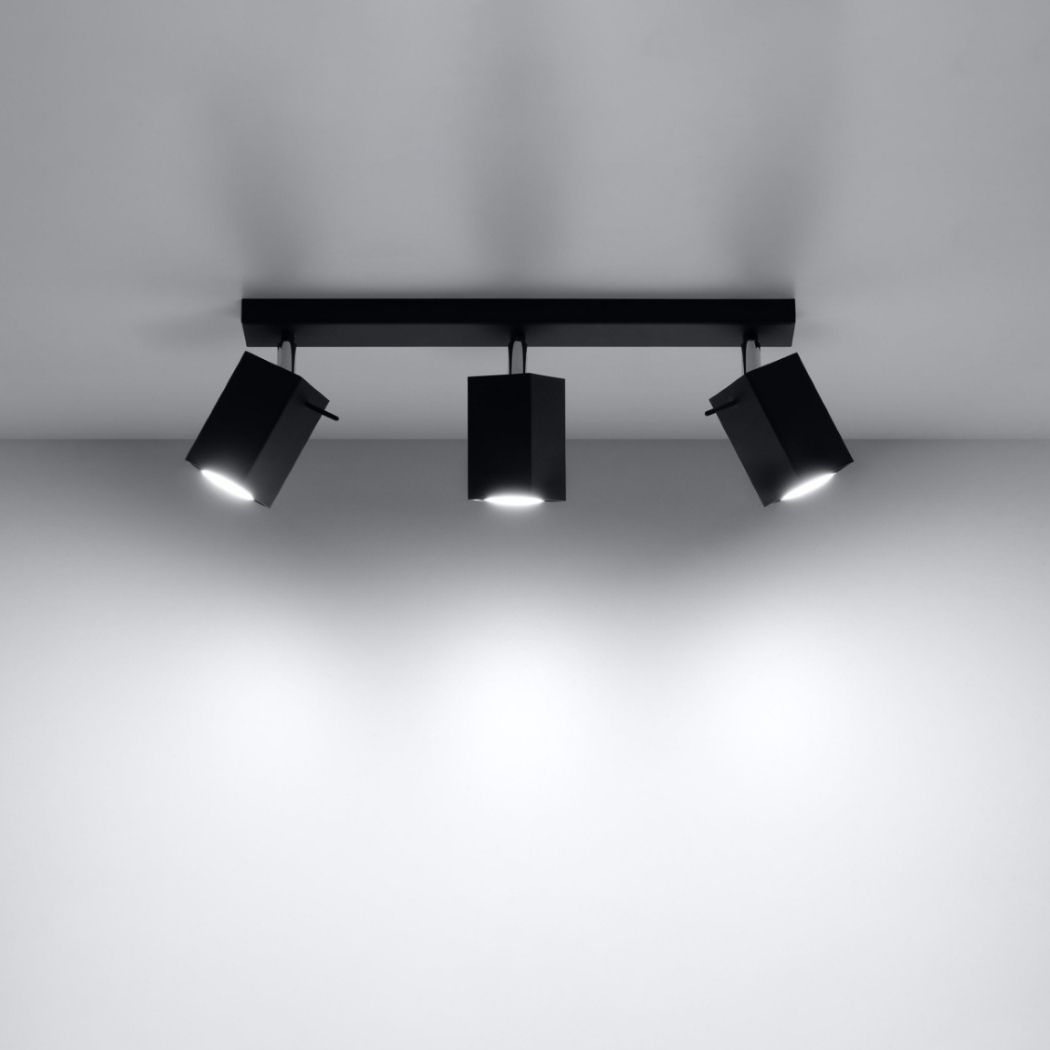 Plafonnier noir à trois spots orientables allumés sur plafond blanc