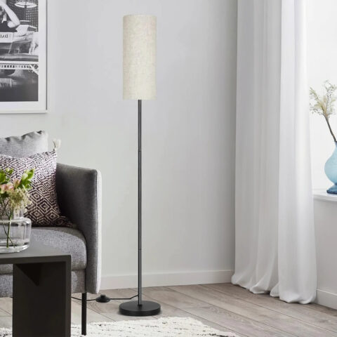 Lampadaire d'angle LED sur pied avec abat-jour en lin, à intensité variable, commande au pied dans un coin de salon.
