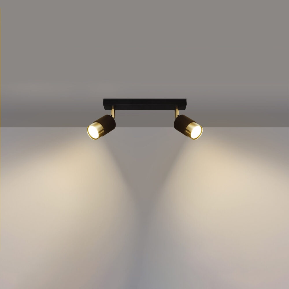 lustre plafonnier orientable design noir et doré composé de deux spots pour éclairage modulable à bras réglables de forme cylindrique sur plafond blanc et mur de fond gris.