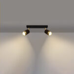 lustre plafonnier orientable design noir et doré composé de deux spots pour éclairage modulable à bras réglables de forme cylindrique sur plafond blanc et mur de fond gris.