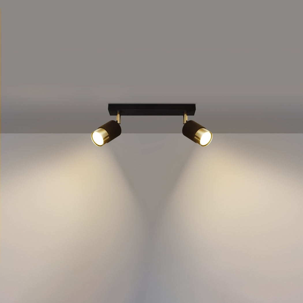 lustre plafonnier orientable design noir et doré composé de deux spots pour éclairage modulable à bras réglables de forme cylindrique sur plafond blanc et mur de fond gris.
