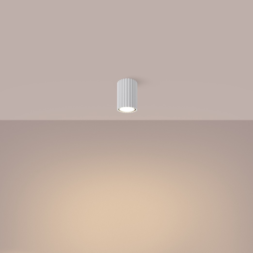 Plafonnier cylindrique blanc nervuré et court diffusant une lumière chaude