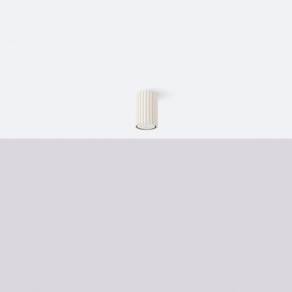 Lustre plafonnier tubulaire design en aluminium beige rainuré fixé au plafond blanc de façon verticale.
