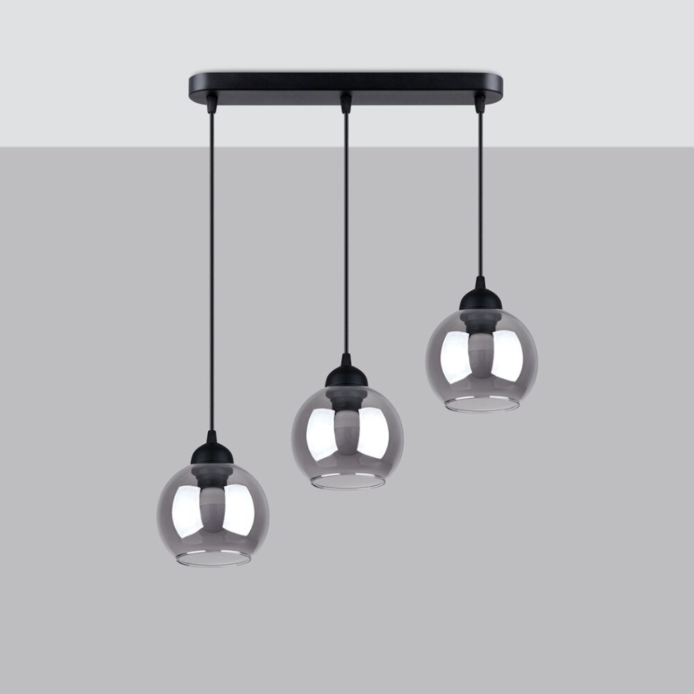 Suspension à trois lampes design en verre fumé de forme ronde suspendu à une base rectangulaire en métal noire fixée au plafond sur un fond gris.