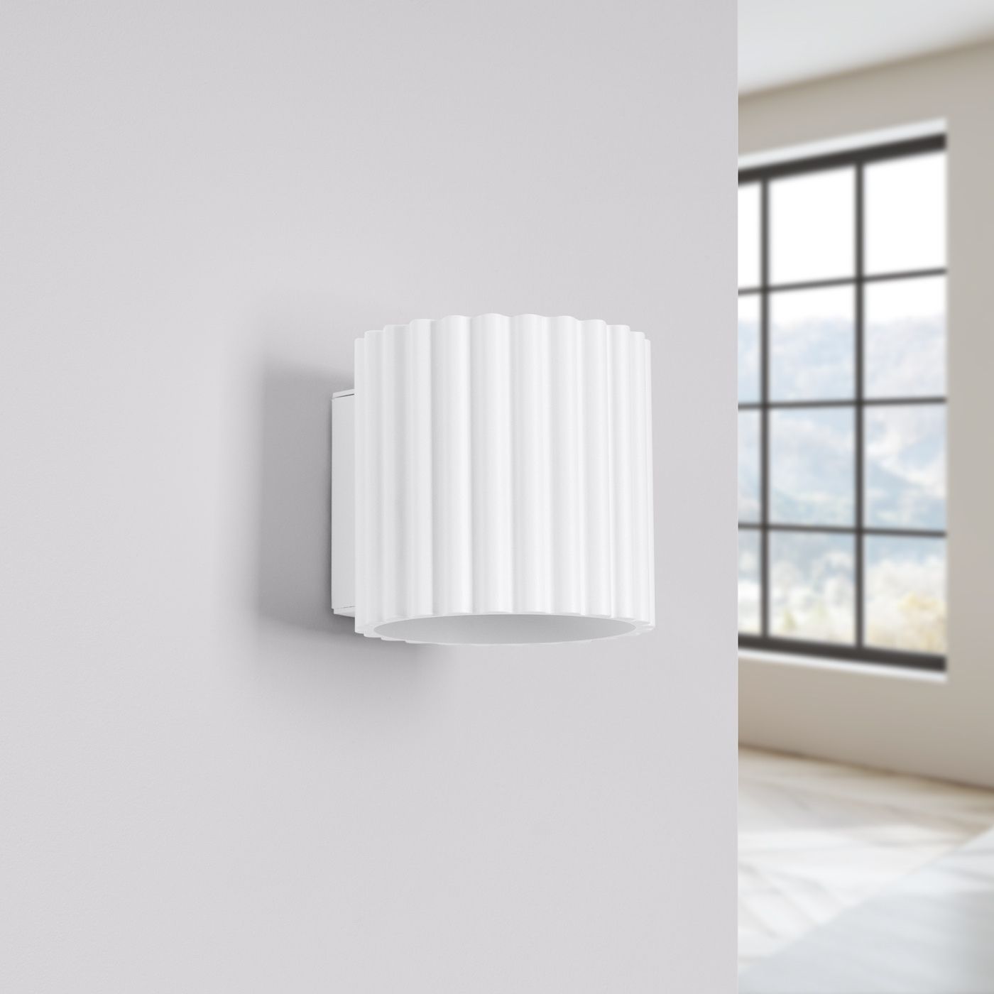 Applique murale blanche de forme cylindrique et texturée sur un mur gris, avec une fenêtre en fond