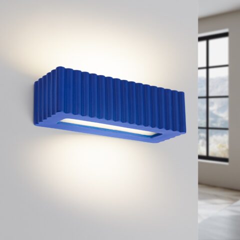 Applique murale design à relief cannelé aux couleurs contemporaines, en céramique bleu vif, fixée sur un mur clair et diffusant une lumière douce vers le haut et le bas.