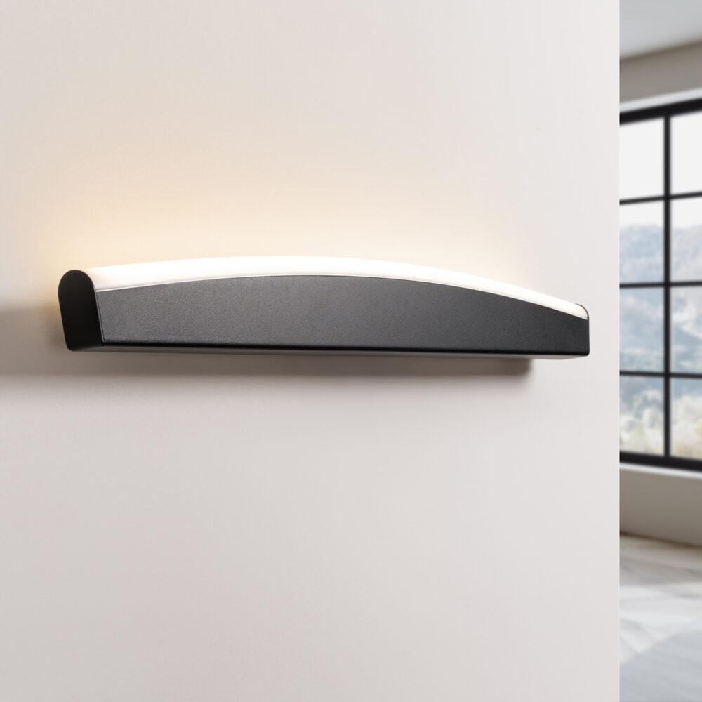 Notre applique murale LED vogue horizontale 3 coloris, noir en l'occurrence, éclairée et fixée sur un mur clair.