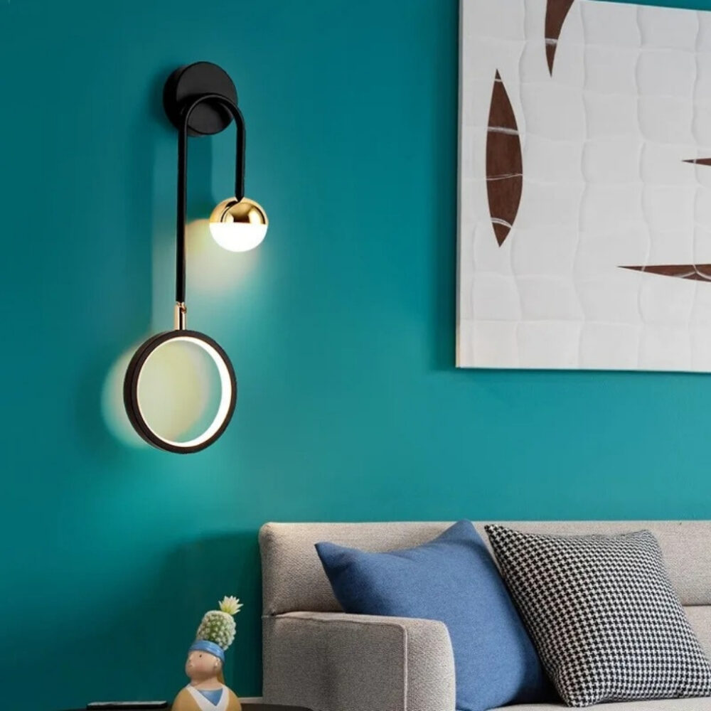 Applique murale noire à bras arqué et disque lumineux blanc sur un mur bleu canard