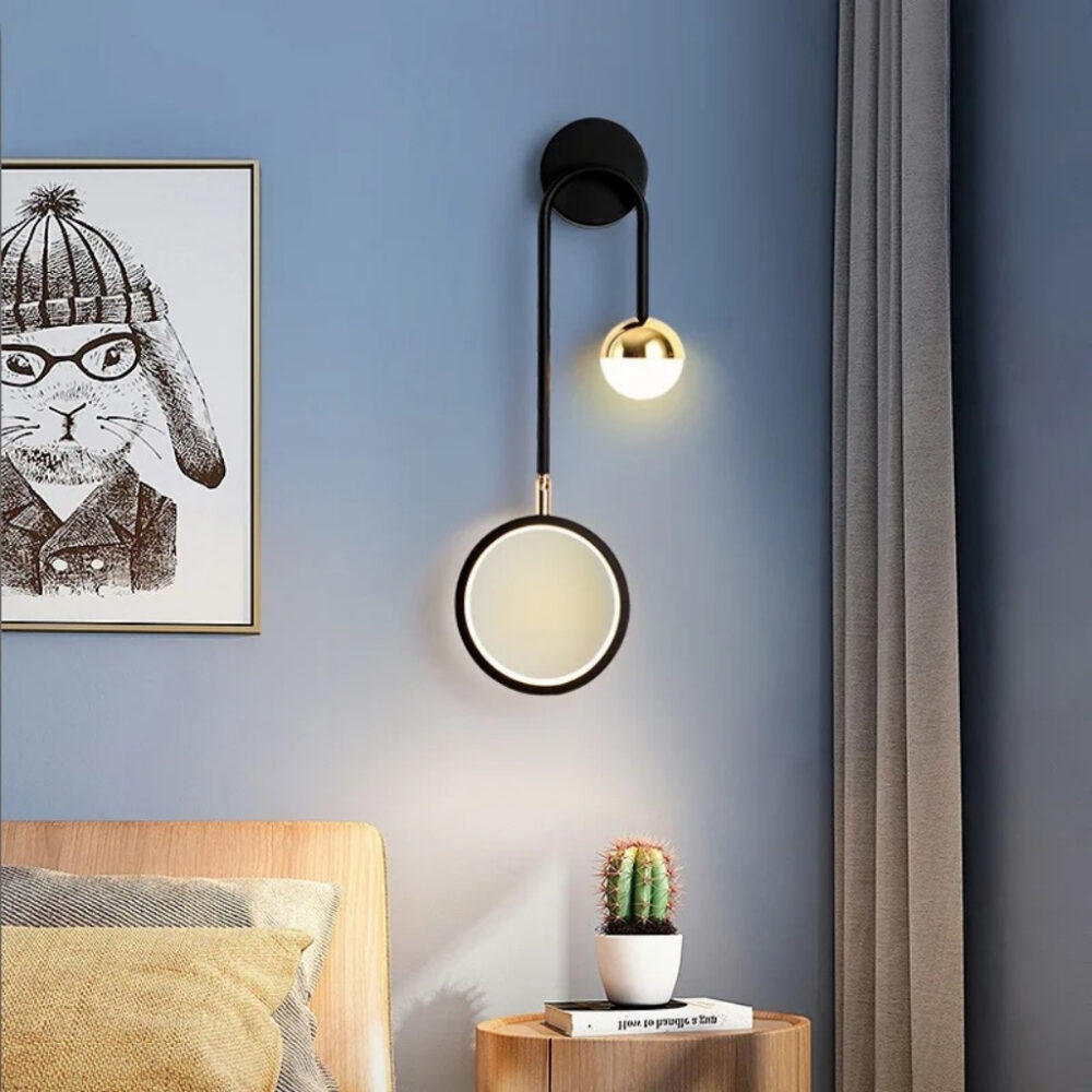 Applique murale noire à bras arqué et disque lumineux blanc dans une chambre avec cactus