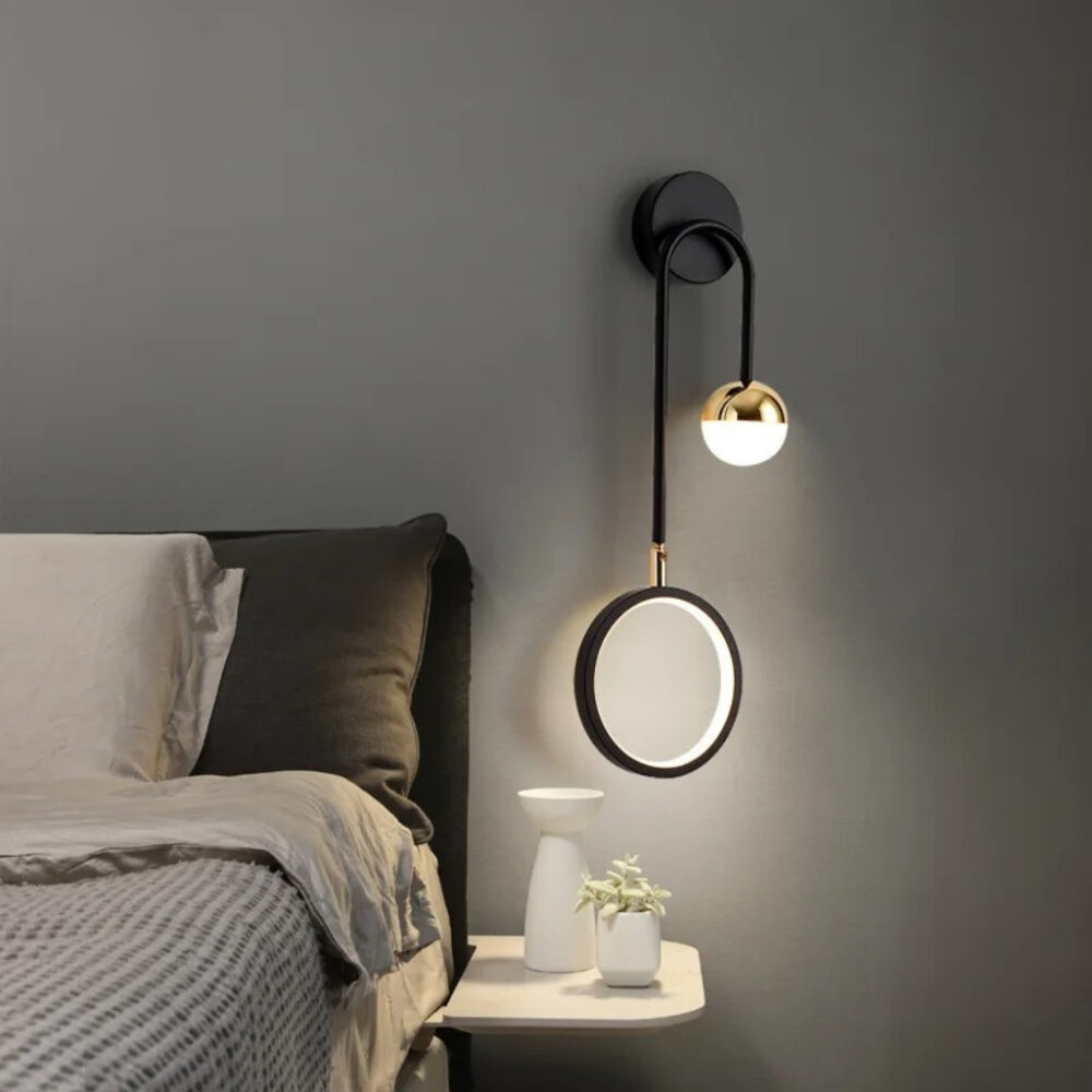 Applique murale noire à bras arqué et disque lumineux blanc près d'un lit gris