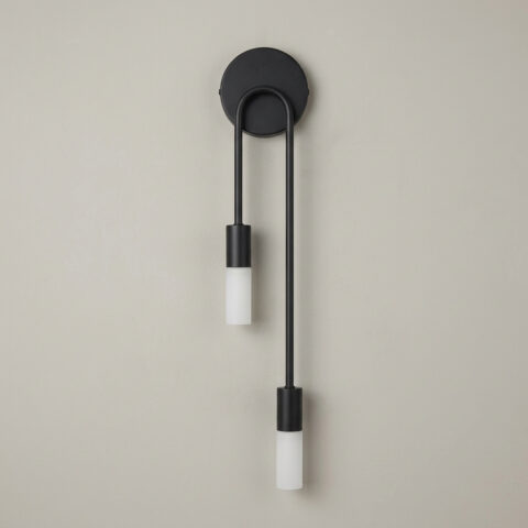 Applique murale moderne et élégante en métal noir avec deux bras de longueurs asymétriques, sur mur gris