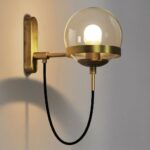 Applique murale au style vintage industriel avec un cordon noir et un globe en verre, sur un mur gris