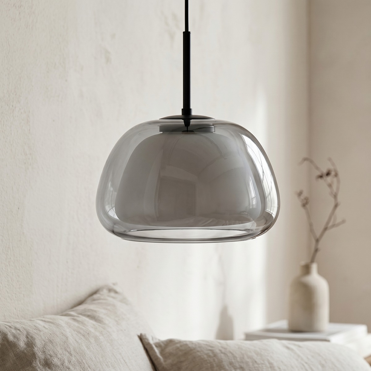 Suspension unique à abat-jour en verre fumé au-dessus d'un canapé crème